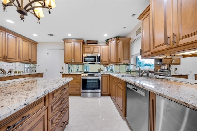 kitchen featuring light stone counters, appliances with stainless steel finishes, and a sink