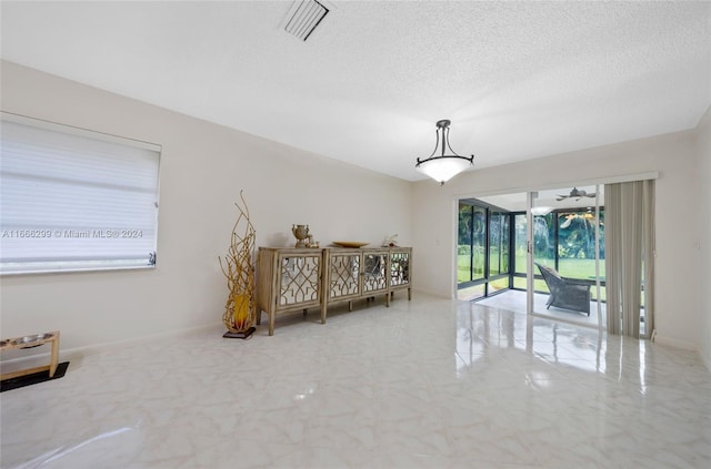 interior space with ceiling fan and a textured ceiling