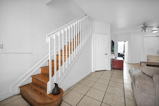 staircase featuring tile patterned flooring and ceiling fan