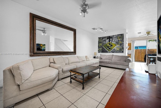 living room with ceiling fan, a textured ceiling, and light tile patterned floors