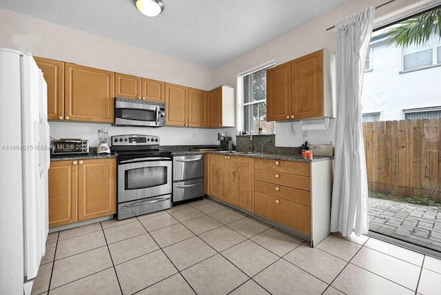 kitchen with sink, appliances with stainless steel finishes, light tile patterned floors, and a healthy amount of sunlight