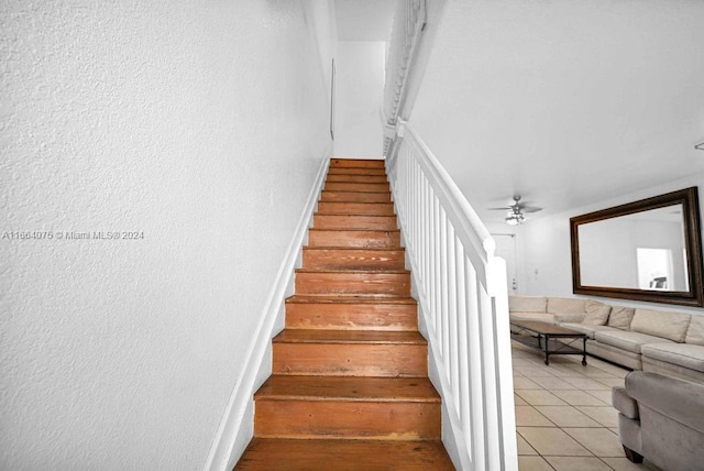 stairway featuring ceiling fan and tile patterned floors