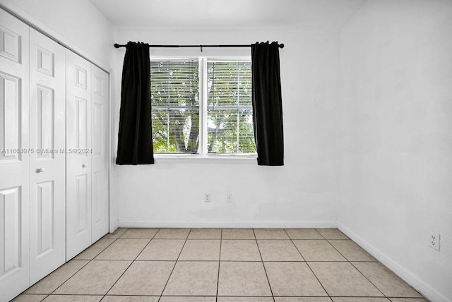 unfurnished bedroom featuring light tile patterned flooring and a closet