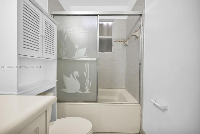 full bathroom with enclosed tub / shower combo, vanity, and toilet