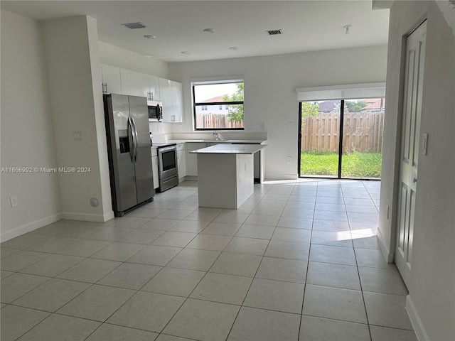 kitchen with light tile patterned flooring, a center island, stainless steel appliances, and white cabinets