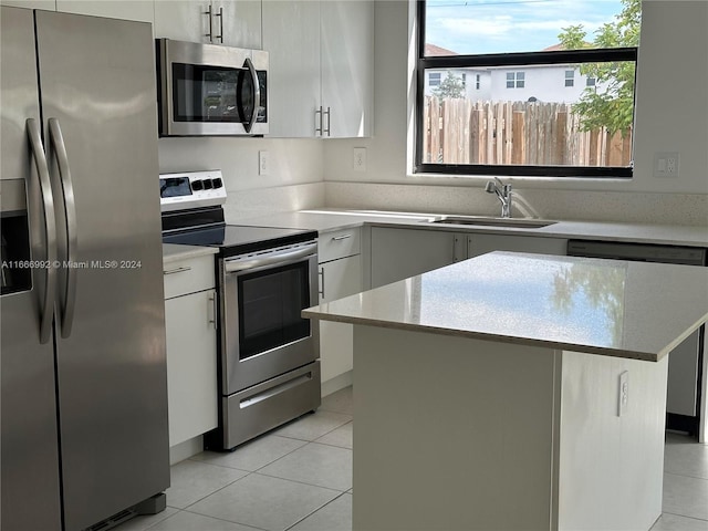 kitchen featuring light tile patterned flooring, white cabinetry, stainless steel appliances, a center island, and sink