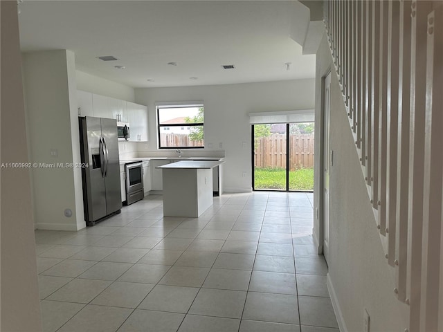 kitchen with sink, white cabinets, a kitchen island, stainless steel appliances, and light tile patterned floors