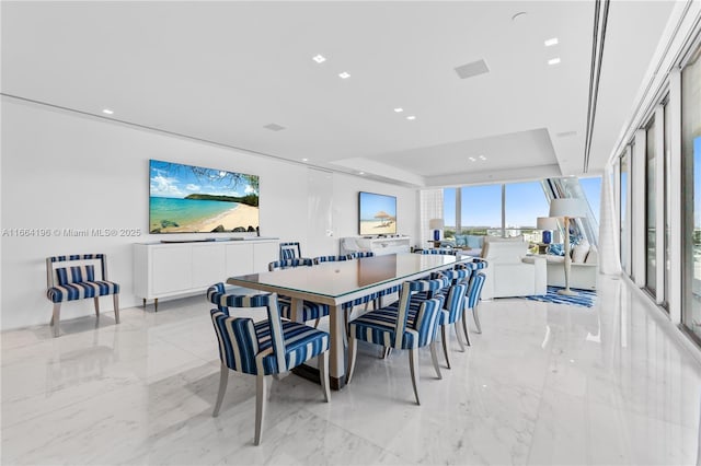 dining space with a raised ceiling, marble finish floor, and recessed lighting
