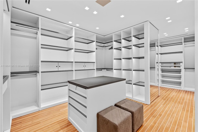 walk in closet with light hardwood / wood-style flooring