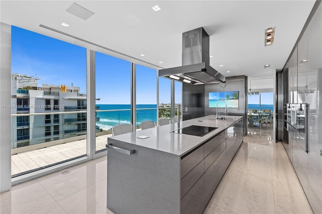 kitchen featuring a large island, a wall of windows, a water view, black electric stovetop, and island exhaust hood