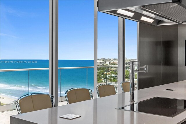 kitchen featuring a water view, kitchen peninsula, ventilation hood, a kitchen bar, and sink