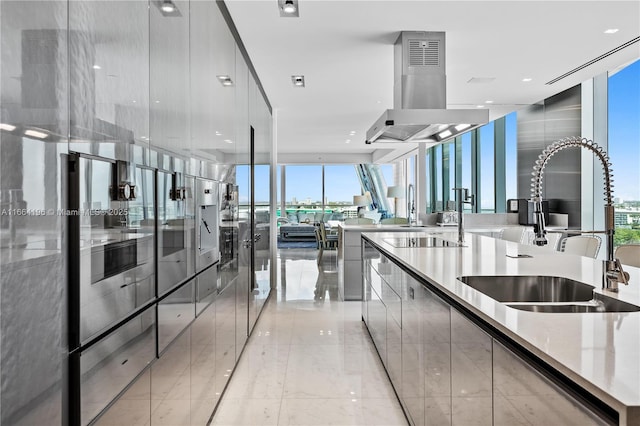 kitchen with sink, island range hood, and a wall of windows