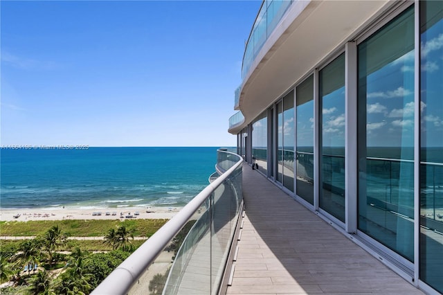 balcony with a water view and a view of the beach