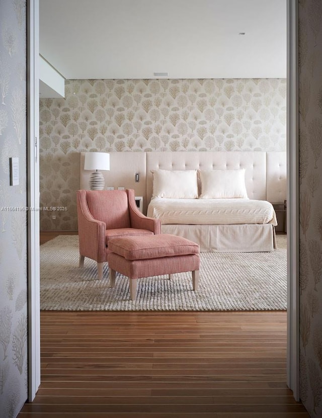 bedroom featuring wallpapered walls and wood finished floors