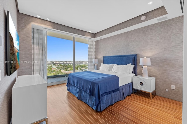 bedroom with wallpapered walls and wood finished floors