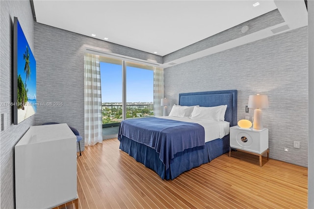 bedroom with wood finished floors and wallpapered walls