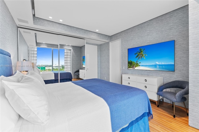 bedroom with light wood finished floors, an accent wall, recessed lighting, and wallpapered walls