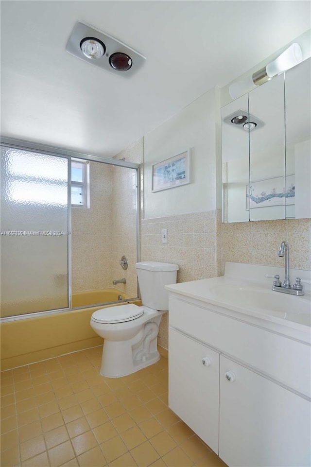 full bathroom with bath / shower combo with glass door, tile walls, toilet, vanity, and tile patterned flooring