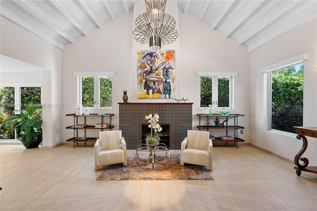 living area with beam ceiling, a fireplace, high vaulted ceiling, and a healthy amount of sunlight