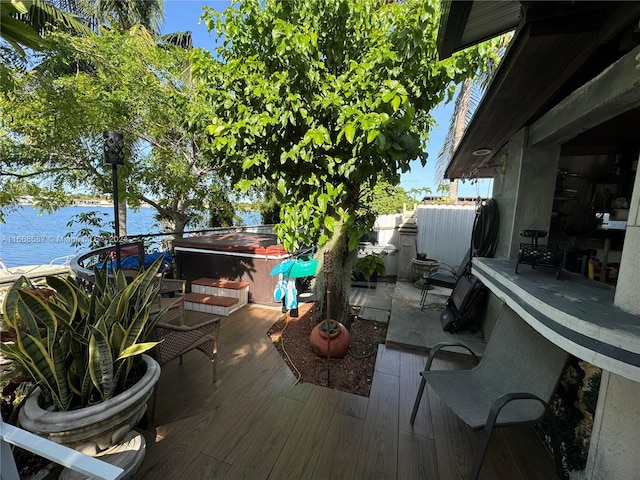 wooden deck with a water view and a jacuzzi