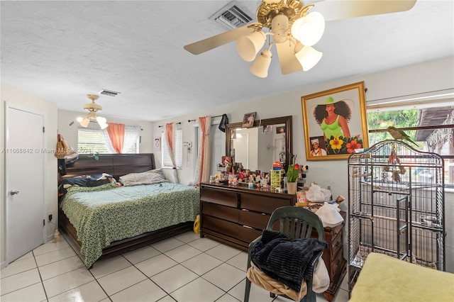 tiled bedroom with ceiling fan and a textured ceiling