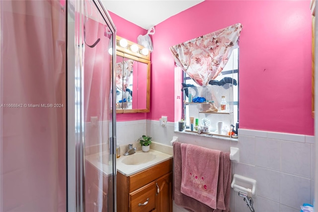 bathroom with walk in shower, vanity, and tile walls