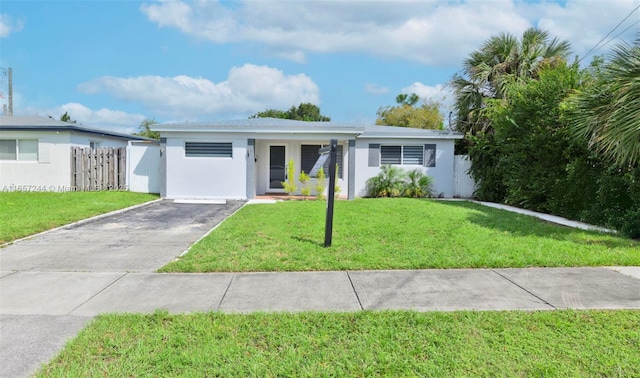 view of front facade with aphalt driveway, a front lawn, fence, and stucco siding