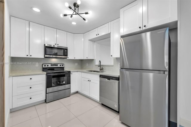 kitchen with tasteful backsplash, white cabinets, stainless steel appliances, light countertops, and a sink