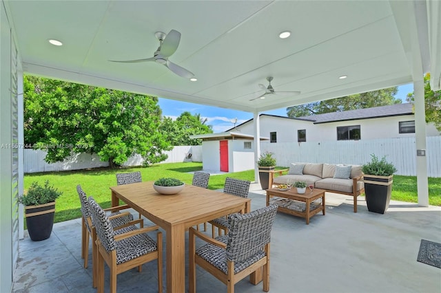 view of patio / terrace featuring an outbuilding, outdoor dining area, ceiling fan, a fenced backyard, and an outdoor living space