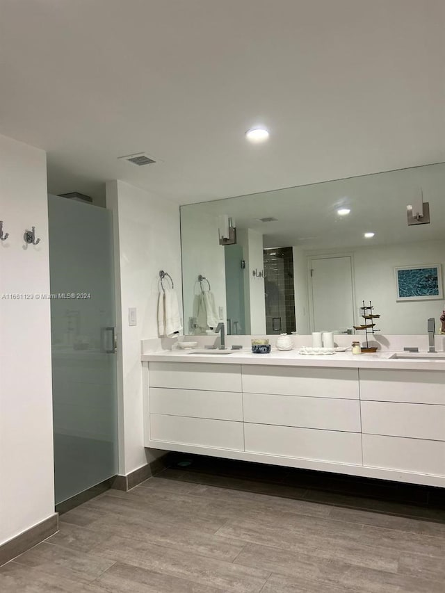 bathroom with hardwood / wood-style floors, a shower with shower door, and vanity