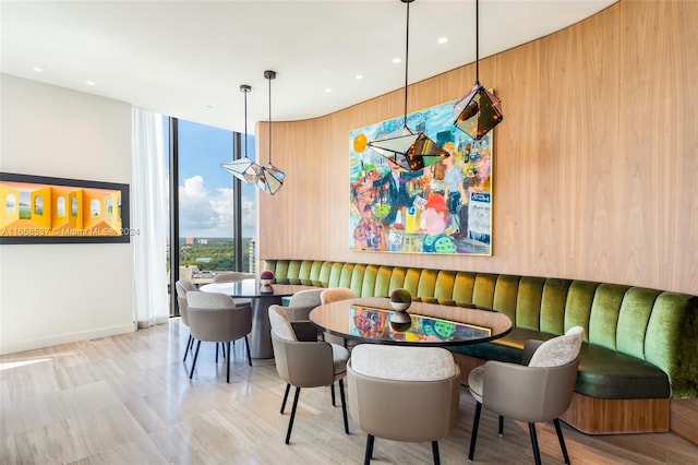 dining area featuring breakfast area, wood walls, and a wall of windows