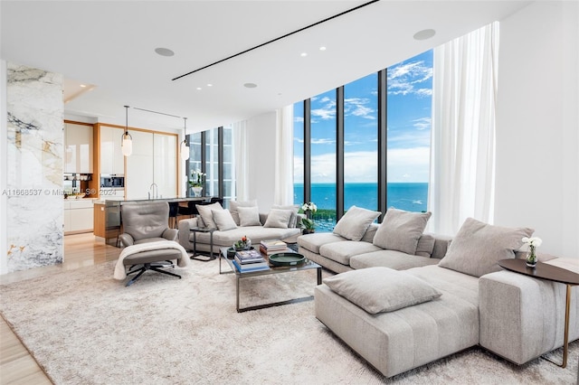 living room with a water view, light hardwood / wood-style floors, and a wall of windows