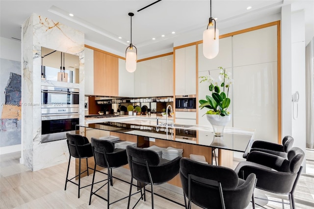 kitchen featuring appliances with stainless steel finishes, hanging light fixtures, white cabinetry, and sink