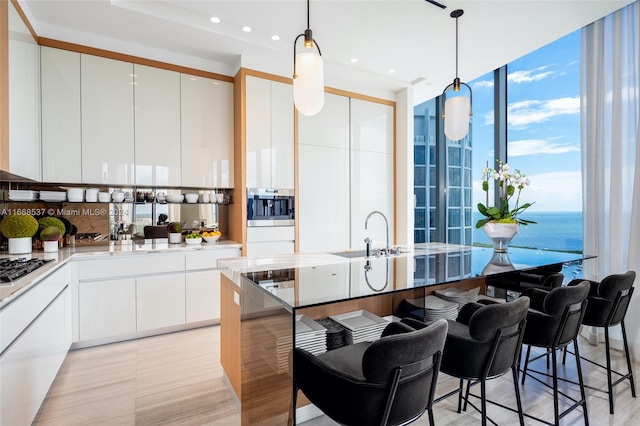 kitchen with white cabinets, decorative light fixtures, oven, and a water view