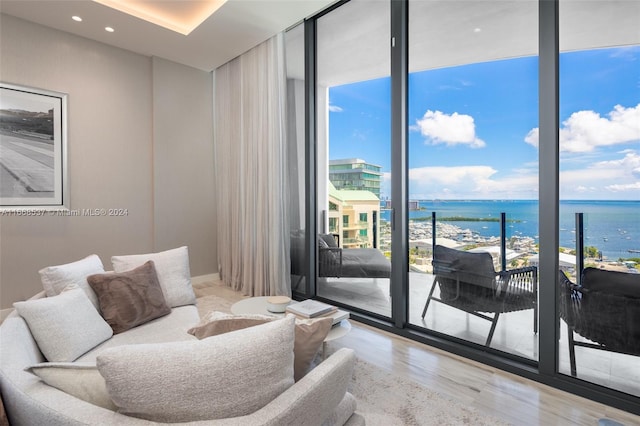 living room with a water view, light hardwood / wood-style floors, a healthy amount of sunlight, and expansive windows