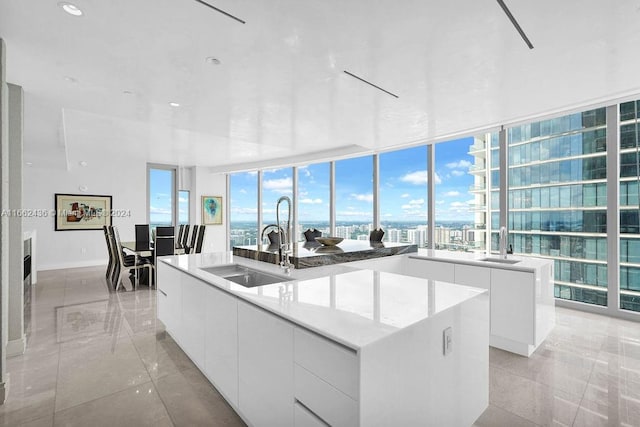 kitchen with white cabinets, an island with sink, sink, and a healthy amount of sunlight