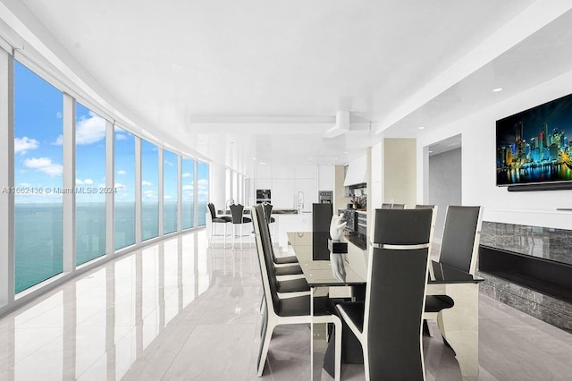 dining area with a water view, light tile patterned floors, and floor to ceiling windows