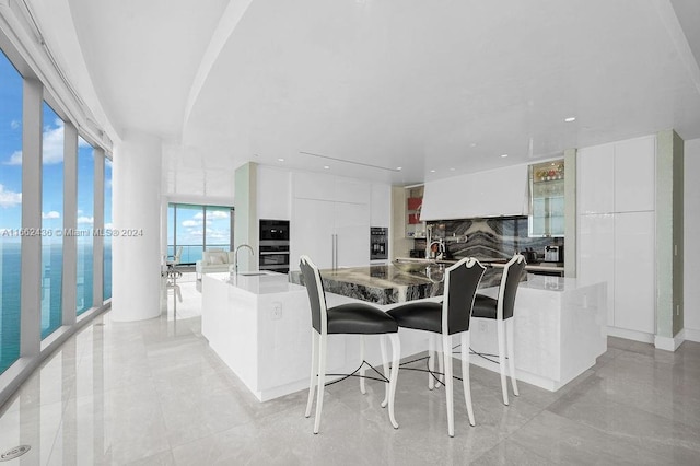 kitchen with a large island, a breakfast bar area, and white cabinetry