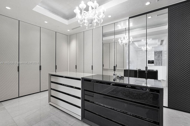 spacious closet with a notable chandelier and a tray ceiling