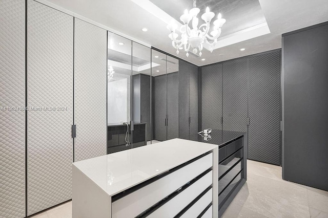 spacious closet featuring a raised ceiling and a notable chandelier