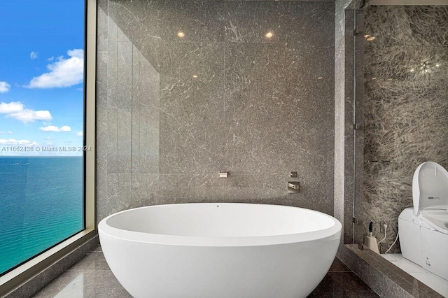 bathroom with tile walls, a bath, and a water view