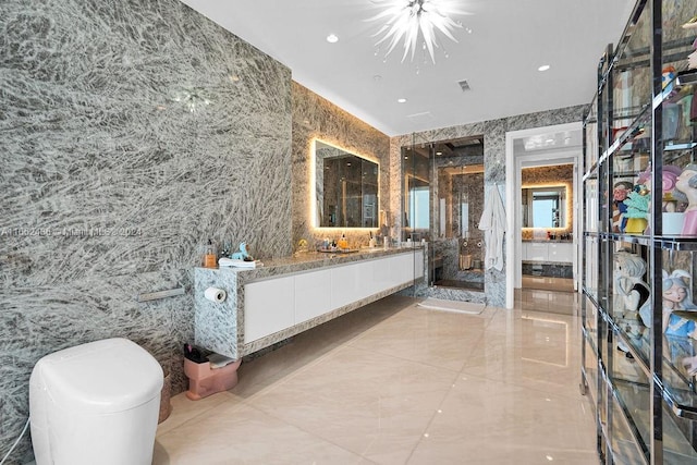 bathroom featuring a chandelier, a shower with shower door, vanity, and tile walls