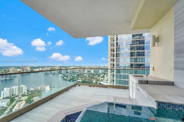 balcony with sink, a water view, and a hot tub