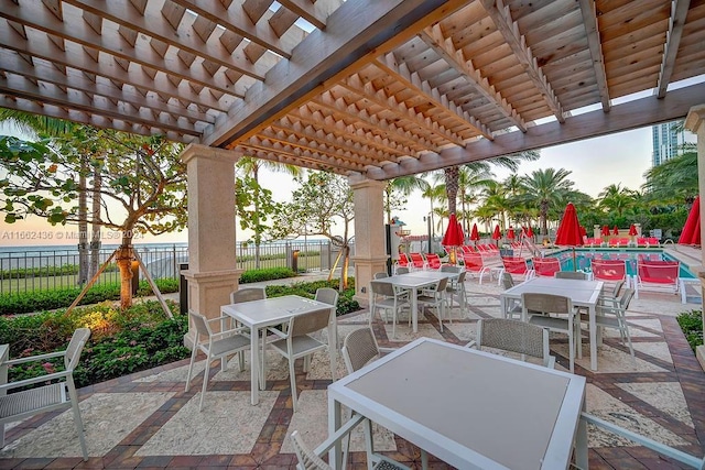 patio terrace at dusk with a pergola and a water view