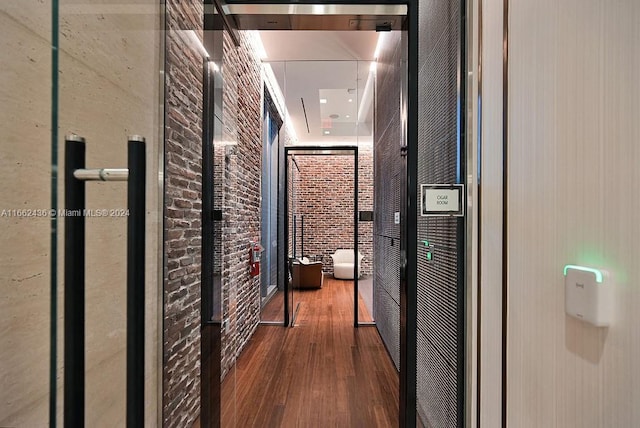 hallway featuring brick wall and wood-type flooring