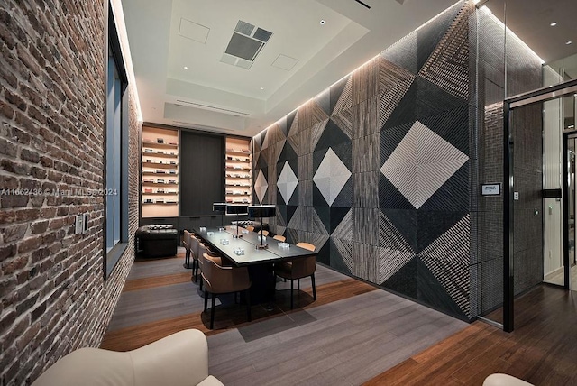 wine cellar with a raised ceiling, brick wall, and hardwood / wood-style floors