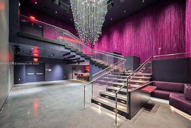 interior space featuring a high ceiling, a chandelier, and concrete flooring