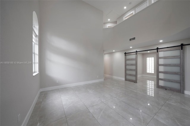 unfurnished living room with a barn door and a high ceiling