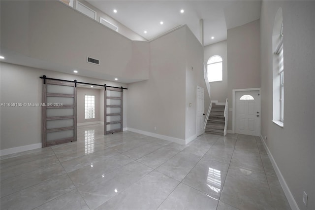 foyer entrance featuring a towering ceiling and a barn door