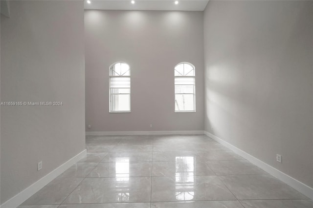 unfurnished room featuring recessed lighting, a high ceiling, and baseboards